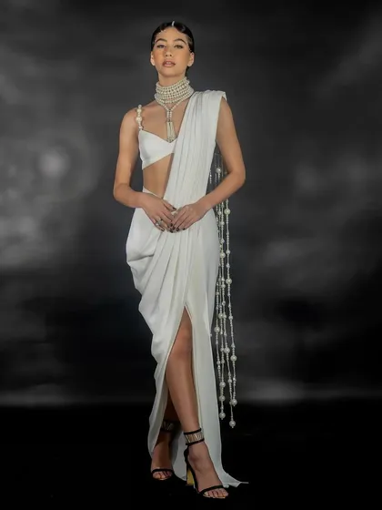 A full-length studio lookbook image for designer Nikhil Thampi's 'Gleam Collection'. This demonstrates my clean and precise studio work, focusing on the modern silhouette, fabric drape, and intricate pearl detailing of the contemporary saree.