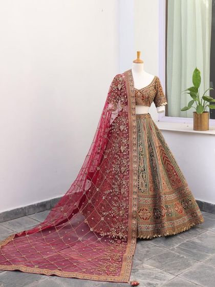 A full view of a multi-color bridal lehenga with a rich maroon dupatta. The trail of the dupatta adds a touch of royalty to this beautiful piece.
