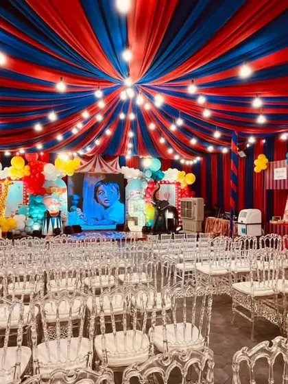 A full venue transformation for a grand carnival themed birthday party. We used bold red and blue ceiling drapes to create a 'big top' tent effect, complete with themed stalls and festive lighting for an immersive experience.