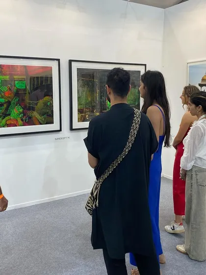 A group of visitors listening as someone explains the details of Sandeep T K's photographs.
