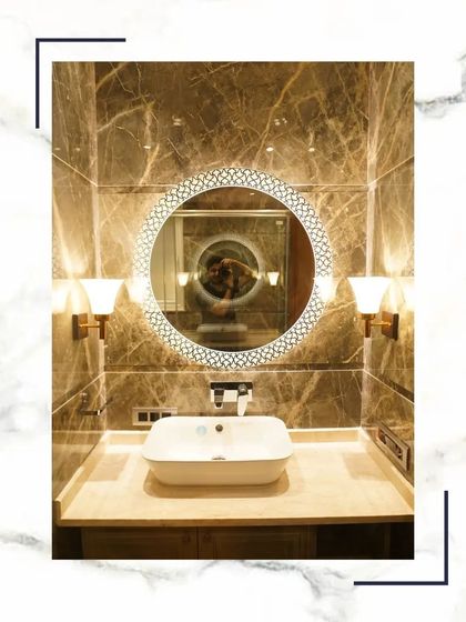 A close-up of a beautiful vanity area, featuring an intricately designed circular mirror, elegant wall sconces, and a modern vessel sink on a marble countertop.