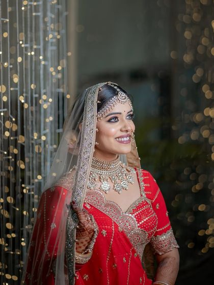 A classic bridal portrait against a backdrop of fairy lights, her makeup looking timeless and elegant.