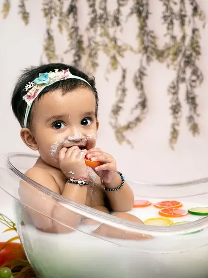 A sweet treat after a fun splash. This little one enjoys a bite of fruit during her milk bath session, showing the playful and unique photo opportunities we can create.
