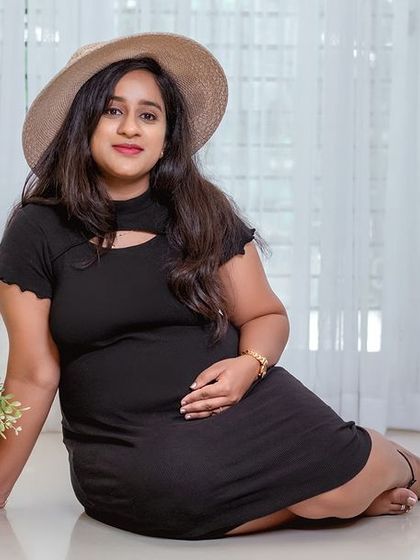 A direct and engaging portrait of the mother-to-be. Her simple black dress and hat create a chic and effortless look.