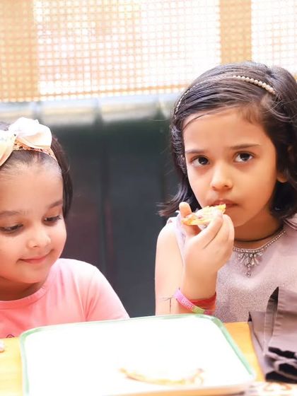 Two little girls sharing a snack and a chat at a birthday party. We document the quiet, sweet moments of friendship.