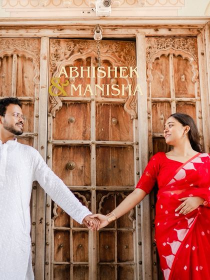 A lovely shot of the couple holding hands in front of a beautifully carved wooden door, their names elegantly overlaid on the image.