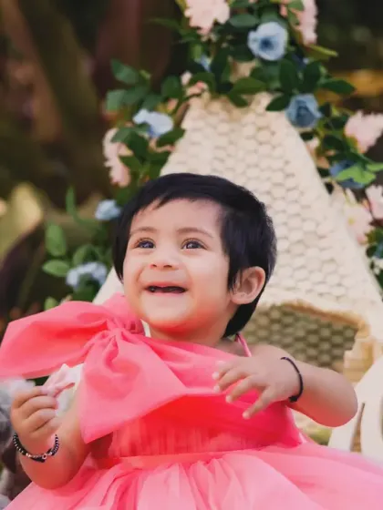 A happy baby girl in a pink dress, enjoying the outdoor teepee setup. Her joyful expression is priceless.