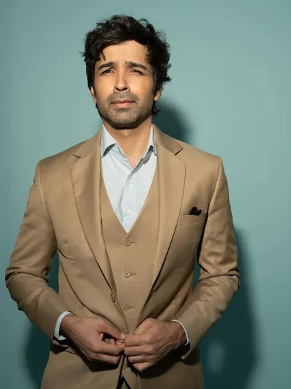 A classic portrait of actor Varun Mitra in a three-piece suit. The clean, light blue background provides a professional and polished look for a corporate or event headshot.