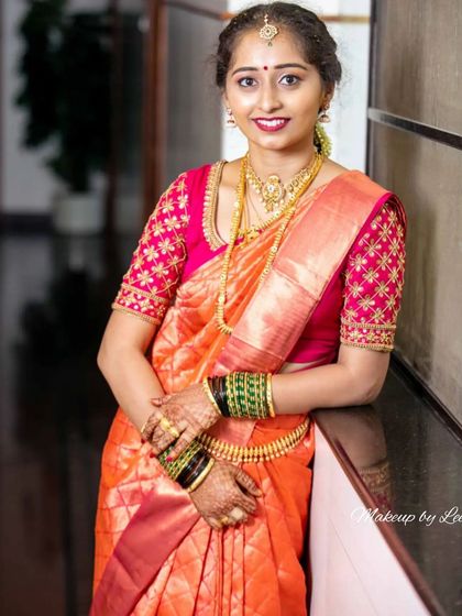 A happy bride posing in her gorgeous orange silk saree and embroidered pink blouse. The makeup is kept elegant and classic to match the richness of her wedding attire.