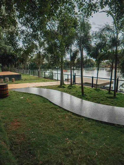 A winding path along the grassy bank of the lake, lined with palm trees and old-fashioned lamps.