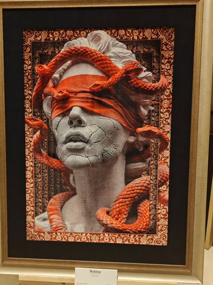 The 'Carpetsia' artwork by Fannan Raza, featuring a blindfolded classical bust entwined with snakes, displayed at the Conrad Bengaluru. This piece is a powerful blend of mythology and textile art.