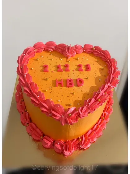 A bright and cheerful heart-shaped cake. The vibrant orange and pink design is a fun and modern way to celebrate a birthday or anniversary.