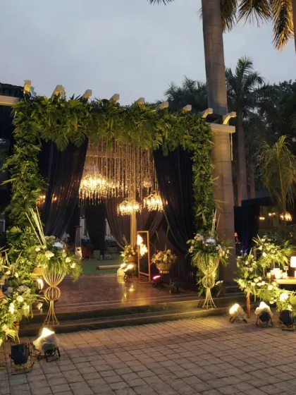 A grand entrance decor with lush greenery, elegant drapery, and crystal chandeliers, setting a lavish tone for the event.