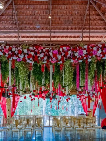 The ambiance of a wedding is essential. Here is an example of our floral decor at the Mahalaxmi Mantap, where cascades of red and white flowers create a breathtaking and sacred space for the ceremony, reflecting a blend of natural beauty and traditional elegance.