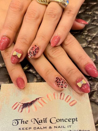 A cute and trendy set of dusty rose almond nails. The design includes accent nails with a hand-painted leopard print and small 3D bows.