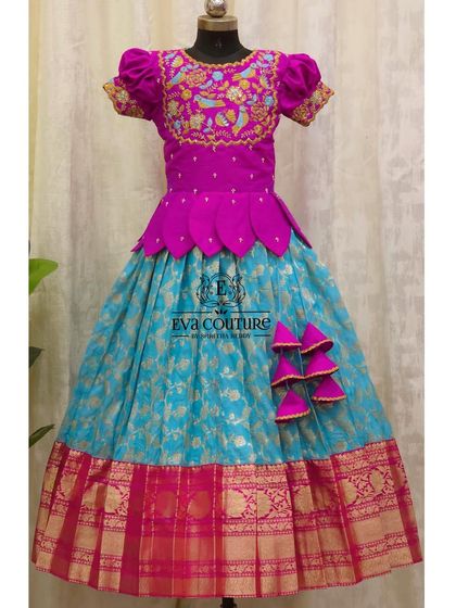 A stunning Banarasi Pattu lehenga in magenta and turquoise. The blouse features intricate bird-motif embroidery, and the skirt has a beautiful gold zari border.