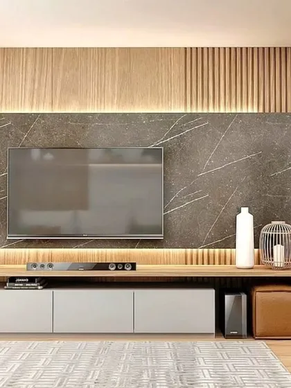 A close-up of a modern TV unit with a wood and marble-finish backdrop. The design includes a low, sleek console with open and closed storage.