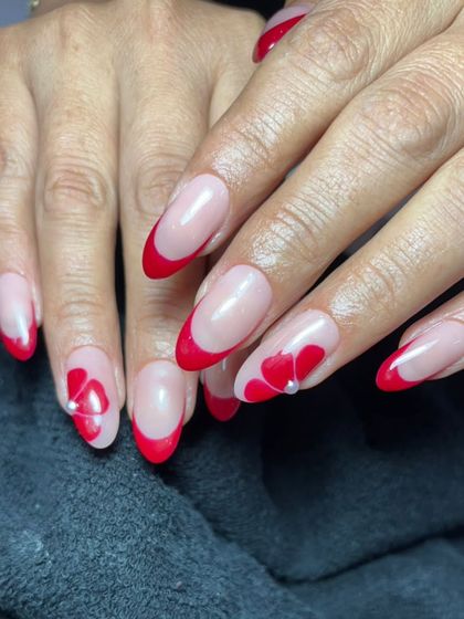 A close-up of the red-tipped French manicure with delicate floral heart details.