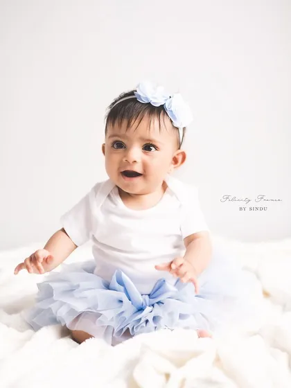 A sweet baby girl in a blue tutu, sitting up proudly. Sitter sessions are the perfect opportunity to show off cute outfits and capture milestone moments.