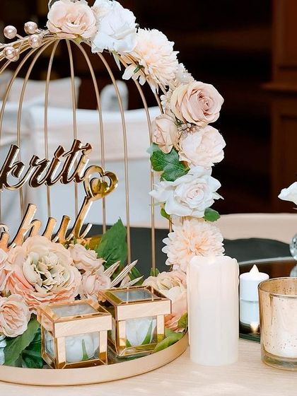 A personalized centerpiece for the couple's table, featuring their names in a golden birdcage adorned with pastel roses. This little detail adds a touch of personal romance to the overall decor.
