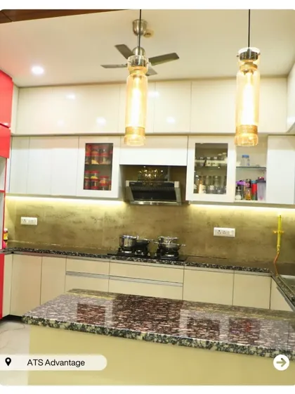 A bright and airy kitchen with cream and red cabinets and a beautiful granite countertop. The hanging pendant lights add a warm, decorative glow.
