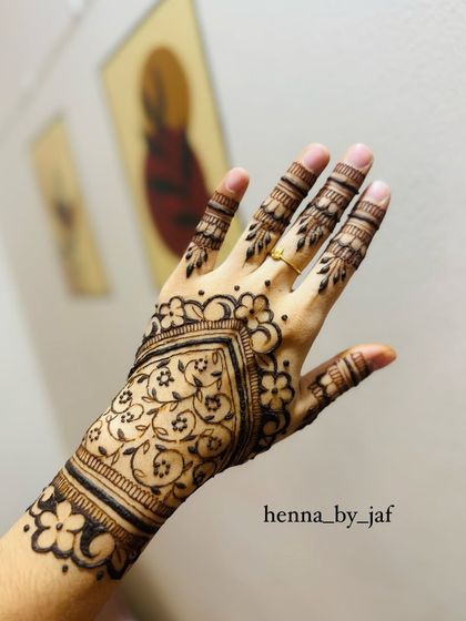 A full view of the completed Gulf style henna, featuring a heart shaped central pattern filled with intricate vines and bordered by flowers.