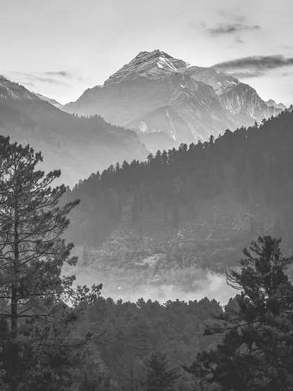 A classic mountain vista in black and white. The fog in the valley and the sharp peak in the distance create a sense of immense scale and atmosphere.
