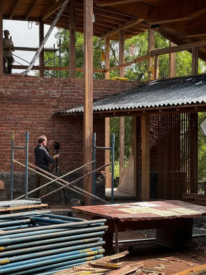 Photographer Ariel Huber captures the farmhouse as the temporary monsoon shed is removed. This moment marks a significant milestone in the construction process, revealing the building's true form.