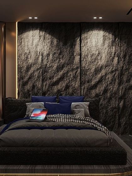 A moody retreat designed for serenity. This dark-toned bedroom features a dramatic raw stone headboard, a low-profile platform bed, and integrated accent lighting to create a warm, inviting atmosphere.