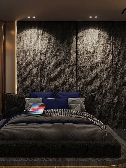 A moody retreat designed for serenity. This dark-toned bedroom features a dramatic raw stone headboard, a low-profile platform bed, and integrated accent lighting to create a warm, inviting atmosphere.
