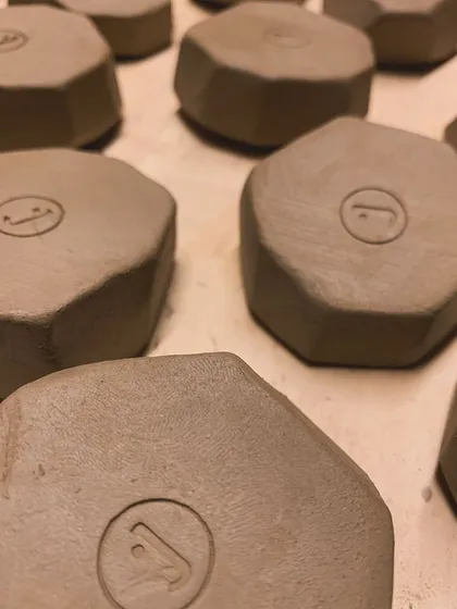 Hexagonal clay pieces, each stamped with our logo, getting ready for a soft launch of our home goods line, The Janbo Living.