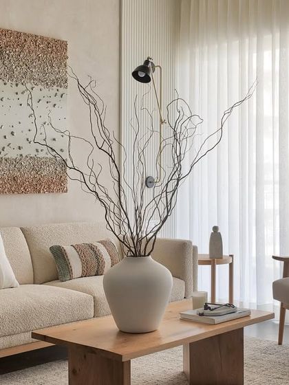This symmetrical, neutral-toned living room is a sanctuary of calmness. The artwork above the sofa complements the textured walls, creating a delightful contrast with the smooth flooring.