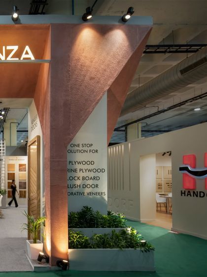 A detail shot of the tapered entrance column at the RP Plywood booth. The integrated planter and uplighting soften the monumental form while highlighting its textured finish.