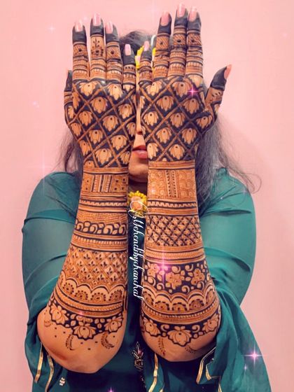 A playful pose showing the back of the hands, covered in dense, beautiful patterns with a rich stain.