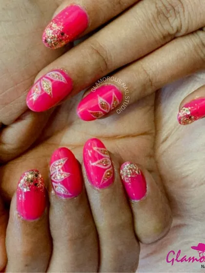 A vibrant and festive design. We used a hot pink base and added gold glitter tips, with accent nails featuring a beautiful, hand-painted leaf design in gold.