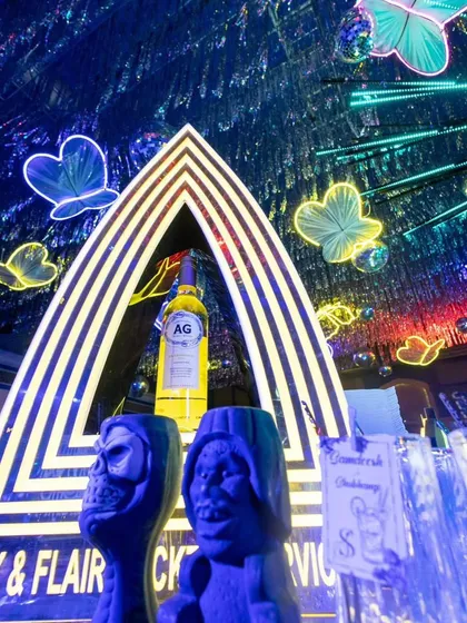 The bar setup for the neon-themed cocktail party, featuring quirky glasses and a custom-branded backdrop.