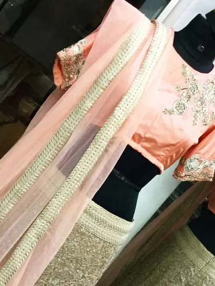This elegant lehenga combines a peach embroidered blouse with a gold sequined skirt. The delicate handwork on the sleeves and neckline adds a touch of sophistication, making it ideal for a bridesmaid or wedding attendee.