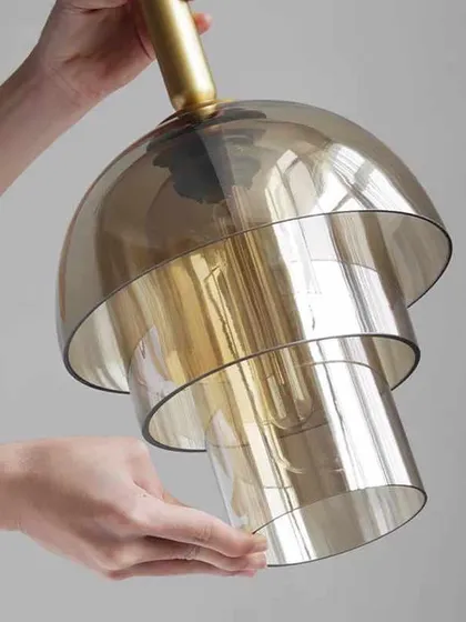 A close-up of a layered glass pendant. The tiered design adds depth and a retro feel, perfect for a kitchen or bar area.