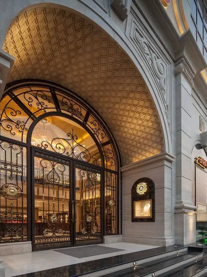 The grand arched entrance of Anand Jewels in Indore is a statement of pure luxury. Intricate metalwork on the doors and a patterned ceiling overhead create a dramatic first impression, symbolic of the exquisite jewellery collection within.