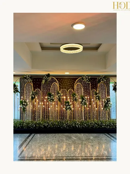 A stunning photo booth backdrop made of golden arches, fairy lights, and floral accents, creating a perfect spot for glamorous photos.
