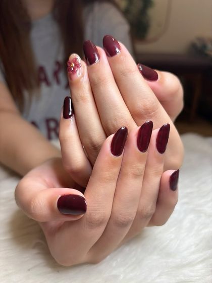 The darks are out already! A rich, glossy maroon manicure on natural nails with a single accent nail featuring a delicate 3D flower.