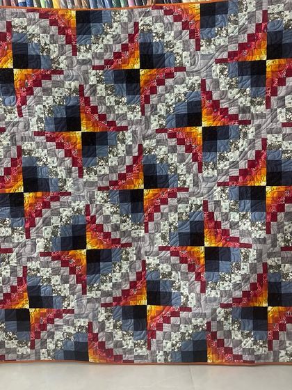 A dynamic quilt with a fiery color palette and a complex, spinning block pattern.