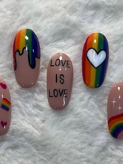 "Love is Love." A set of nails created for Pride Month, featuring rainbows, hearts, and a powerful message.