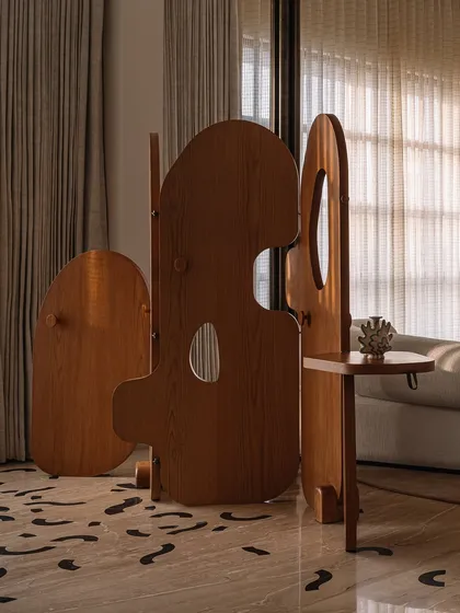 Our 'Hide N Seek' screen is furniture that invites play. Designed to divide a large suite into a salon and bedroom, its amoebic wooden panels have organic cutouts that frame views and create intriguing vignettes. It’s a sculptural piece that is both a space divider and an interactive art form.
