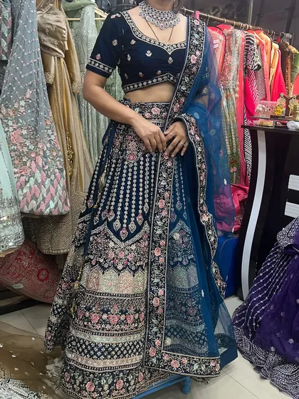A full look at the royal blue velvet bridal lehenga, showing the contrast of the floral embroidery against the deep blue fabric. The matching net dupatta completes the ensemble.