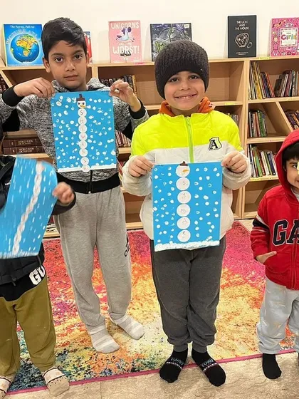 A group of friends proudly displaying their snowman crafts from the winter camp. It’s wonderful to see them create together and celebrate each other's work.