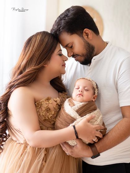 An intimate portrait of a new family of three. The soft lighting and close embrace create a feeling of warmth and security.