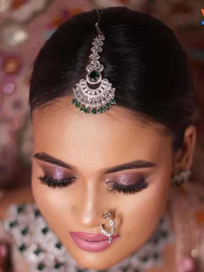 A close-up of a modern bridal look with a focus on shimmery purple eyeshadow and a diamond-studded nose ring.