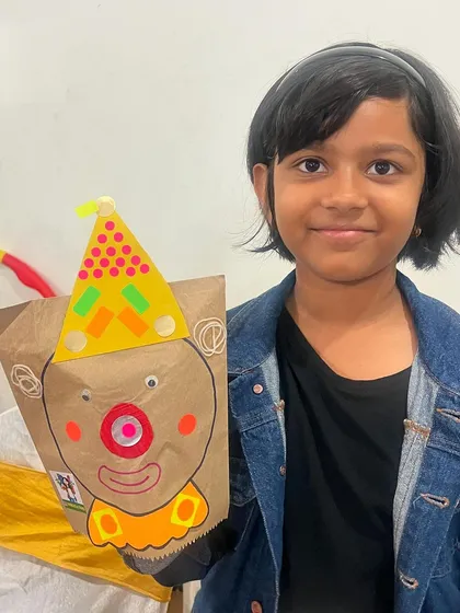 A young girl shows off the colorful clown paper bag puppet she made. I love seeing the unique personality each child brings to their creation.