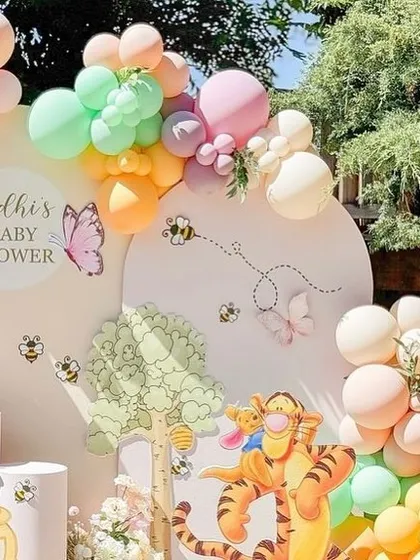 A wide view of the pastel-colored Winnie the Pooh baby shower, perfect for an outdoor event with natural lighting.